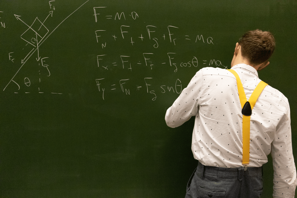 Een bijles docent legt een formule uit op een krijtbord.